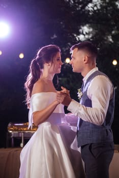 the first wedding dance of the bride and groom inside the restaurant hall in sunset light