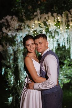 young couple of newlyweds on the evening illuminated arch