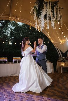 the first wedding dance of the bride and groom inside the restaurant hall in sunset light