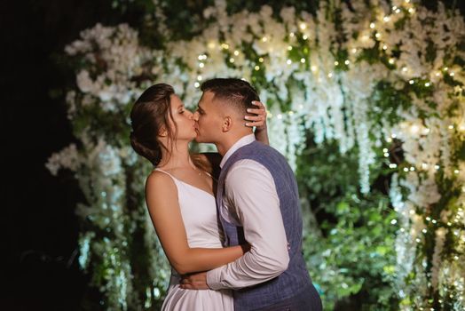 young couple of newlyweds on the evening illuminated arch