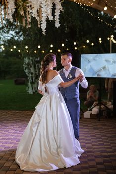 the first wedding dance of the bride and groom inside the restaurant hall in sunset light