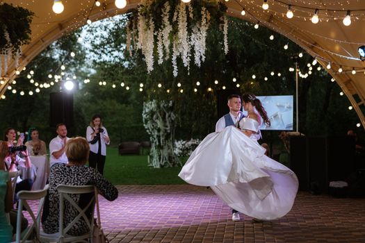 the first wedding dance of the bride and groom inside the restaurant hall in sunset light