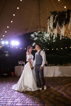 the first wedding dance of the bride and groom inside the restaurant hall in sunset light