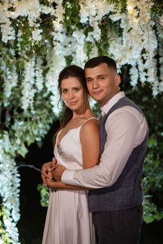 young couple of newlyweds on the evening illuminated arch