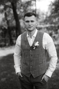 portrait of the groom in a light gray suit outdoors