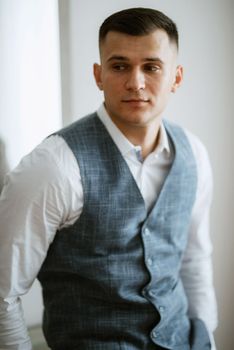 portrait of the groom in a light gray suit indoors