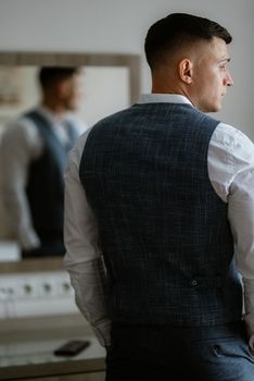 portrait of the groom in a light gray suit indoors