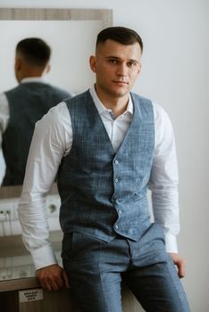 portrait of the groom in a light gray suit indoors