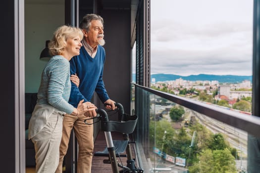 Elderly married couple out in the balcony looking at the view of the city. High quality photo