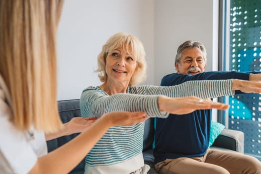 Young blonde woman caregiver helping senior married couple at home. Nurse assisting her senior patients at nursing home. Senior couple being helped by nurse at home. High quality photo