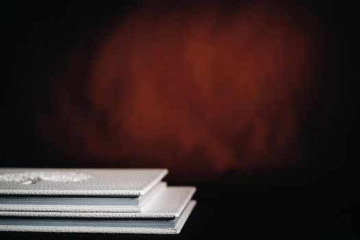 Composition of photo books in natural white leather of different sizes. The white paper on a dark background