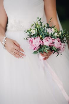 wedding bouquet with peonies in the hands of the bride under the veil.Morning of the bride.