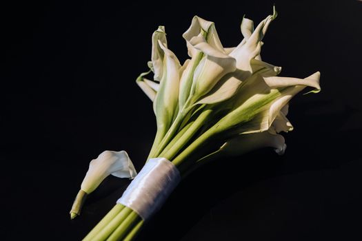 Wedding bouquet of white Calla lilies on a black background.