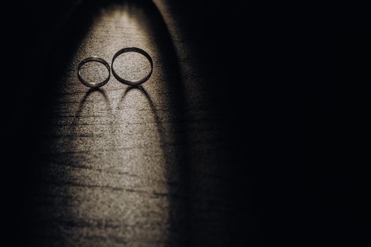 Close-up of two gold wedding rings on a black background.