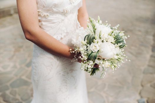 wedding bouquet with peonies in the hands of the bride under the veil.Morning of the bride.