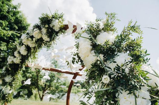 Wedding ceremony on the street on the green lawn.Decor with fresh flowers arches for the ceremony.