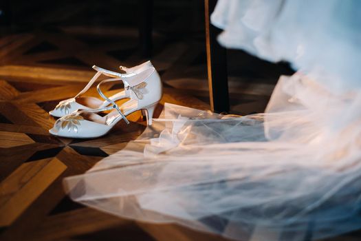 white wedding shoes standing on the field near the dress.