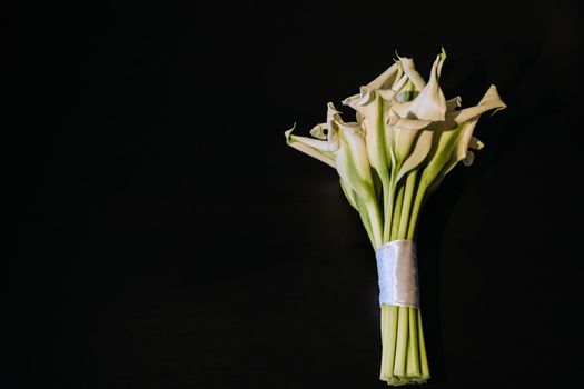 Wedding bouquet of white Calla lilies on a black background.