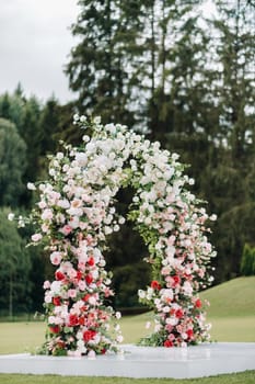 Wedding ceremony on the street on the green lawn.Decor with fresh flowers arches for the ceremony.