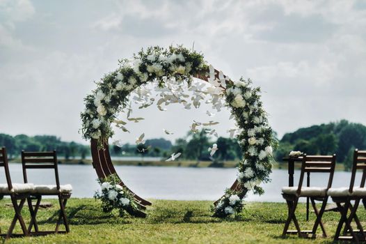 Wedding ceremony on the street on the green lawn.Decor with fresh flowers arches for the ceremony.