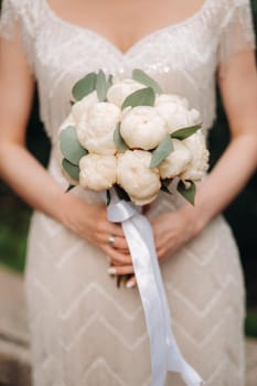 wedding bouquet with peonies in the hands of the bride at the wedding.