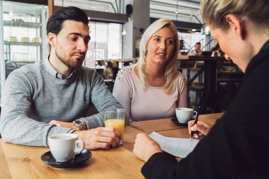 Meeting with clients. Caucasian woman, designer, meeting with her clients, sitting by the desk, consulting on a project. Business meeting. Caucasian people having a meeting in an office.