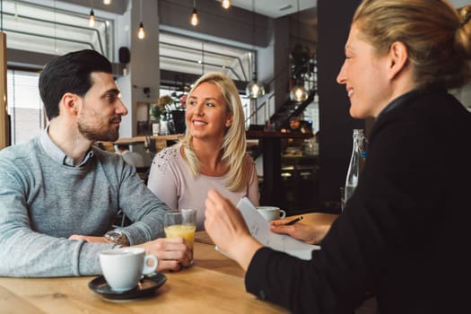 Meeting with clients. Caucasian woman, designer, meeting with her clients, sitting by the desk, consulting on a project. Business meeting. Caucasian people having a meeting in an office.