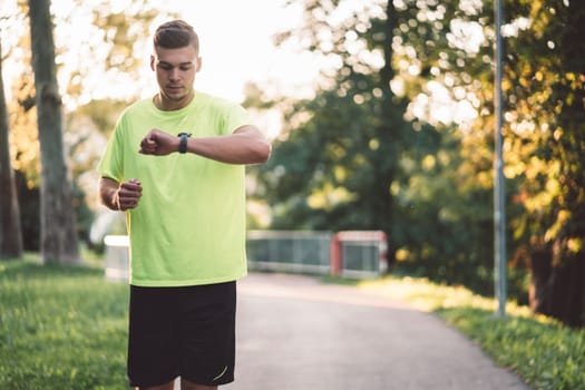 Fit man checking smart watch wearable technology sport smartwatch on workout outside. Man wearing smart watch during his training, measuring his activity. High quality photo