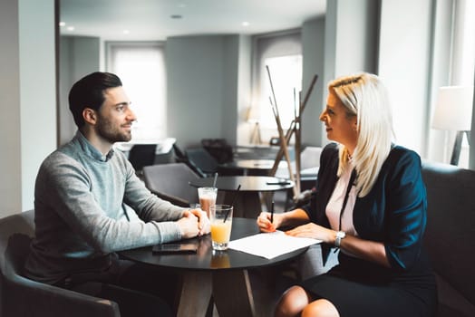 Meeting with clients. Caucasian woman, designer, meeting with her clients, sitting by the desk, consulting on a project. Business meeting. Caucasian people having a meeting in an office.