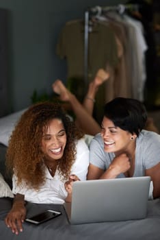 A romantic comedy is always a winner with us. a young couple using a laptop while lying on their bed