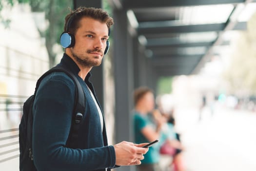 Beautiful caucasian man living in the city. Man spending his day in the city, sun is shining, weather is nice. Young millennial person living in the city, doing his daily errands always using his digital devices, tablet or phone.