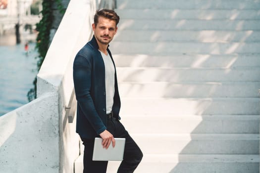 Beautiful caucasian man living in the city. Man spending his day in the city, sun is shining, weather is nice. Young millennial person living in the city, doing his daily errands always using his digital devices, tablet or phone.