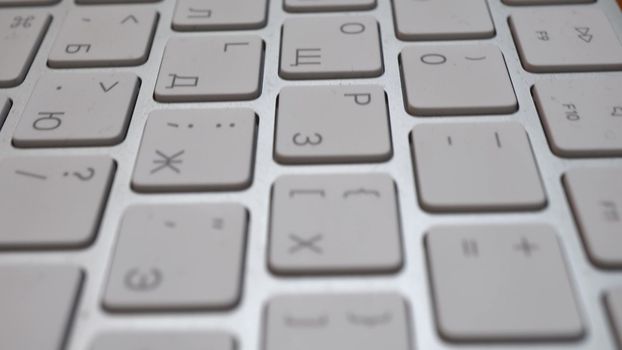 Wireless thin keyboard close -up. The keys are white. Camer slides approaching the object. Macro. 4k