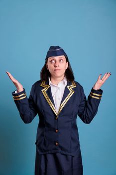Young confused stewardess shrugging shoulders, showing unsure gesture, looking upwards. Flight attendant with doubtful facial expression, puzzled air hostess, uncertain sign