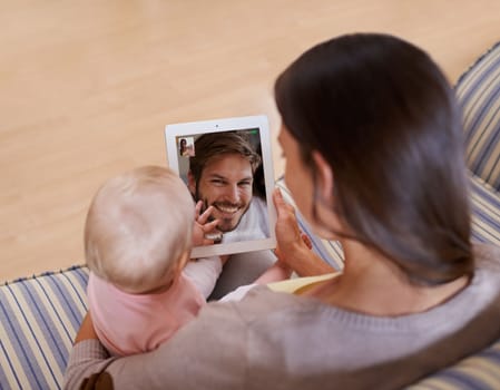 Say hi to Daddy. a happy mother showing her baby daughter a picture of her father on a digital tablet