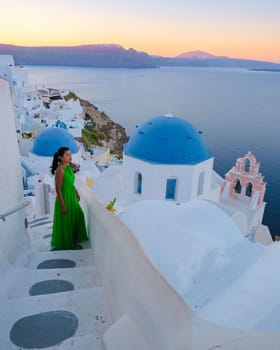 Asian women visit the whitewashed Greek village of Oia Santorini.