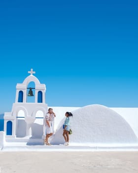 Couple on vacation in Santorini Greece, and men and women at the Greek village of Oia with a view over the ocean during summer vacation