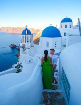 Couple on vacation in Santorini Greece, and men and women at the Greek village of Oia with a view over the ocean during summer vacation