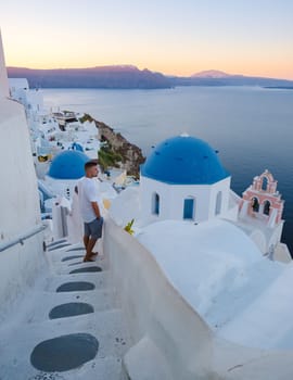 A young man on vacation in Santorini Greece, men visit the whitewashed Greek village of Oia during sunrise