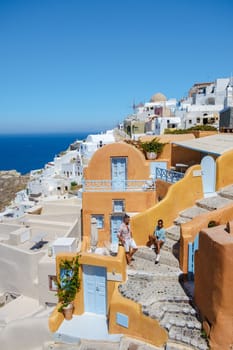 Couple on vacation in Santorini Greece, and men and women at the Greek village of Oia with a view over the ocean during summer vacation