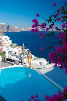 Couple on vacation in Greece, men and women relaxing by a swimming pool of a luxury resort during summer vacation