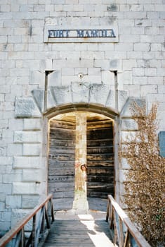 Girl peeks out from behind the ajar wooden door of Mamula Fort. High quality photo