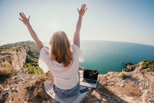 Woman sea laptop. Business woman in yellow hat working on laptop by sea. Close up on hands of pretty lady typing on computer outdoors summer day. Freelance, digital nomad, travel and holidays concept.