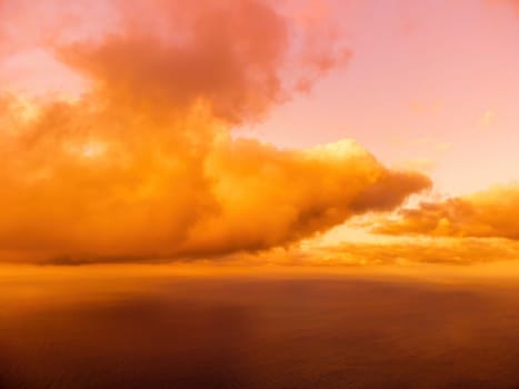 A red burning sunset with the silhouette of a cliff over the sea. Abstract nature summer or spring ocean sea background. Small waves on golden warm water surface with bokeh lights from sun.