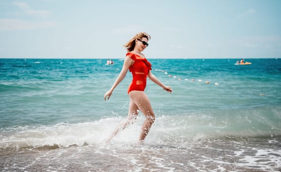 Young happy woman walks carefree on the seaside. Happy lady in red bikini. Portrait beautiful young woman relax smile around beach sea ocean in holiday vacation travel trip.