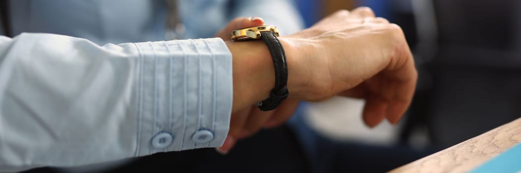 Business woman boss checks time on clock in office closeup. Working day and time planning