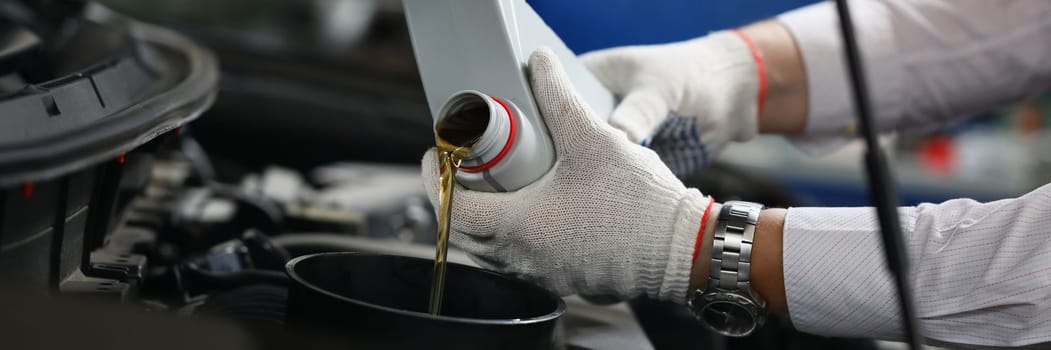Mechanical filling of oil into car in repair garage. Changing oil in engine of car service center