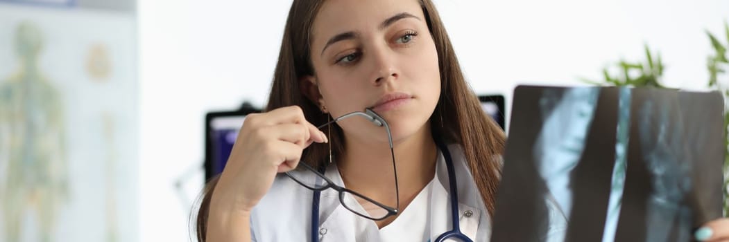 Worried female doctor examining an x-ray of patient. Algorithm for analyzing image quality of radiograph