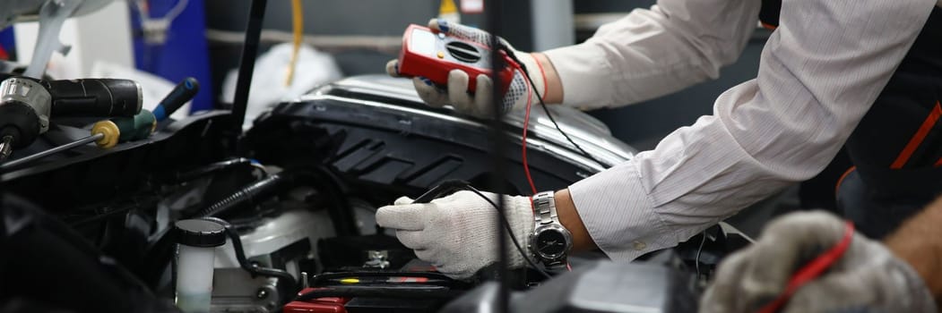 Car repair technicians use voltage multimeter to work in auto repair shops. Diagnostics of car engine breakdowns