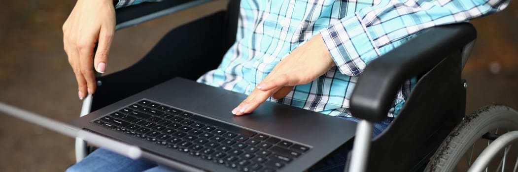 Woman in wheelchair in park with laptop on lap closeup. Remote work freelance and training for the disabled